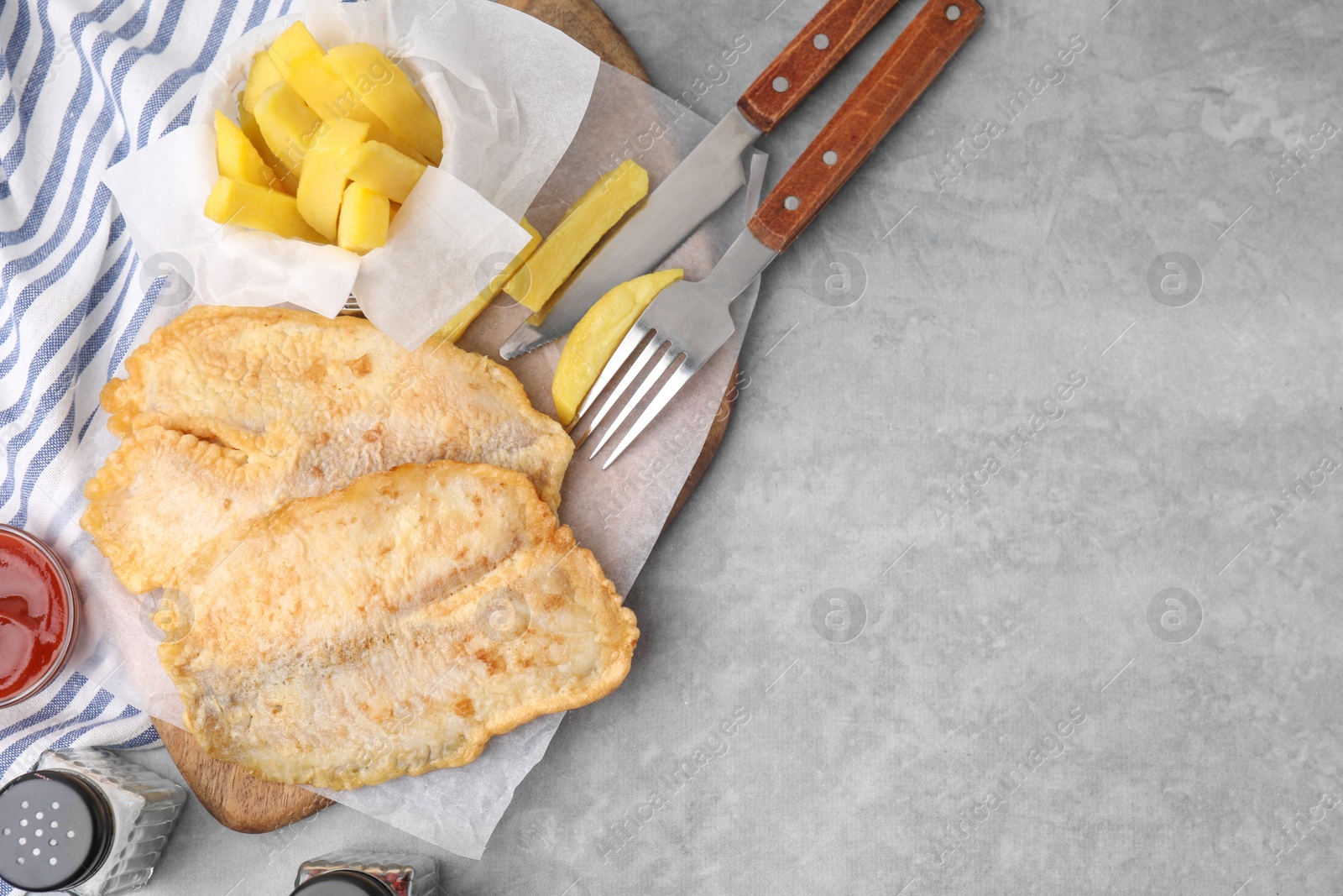 Photo of Delicious fish and chips served on gray table, flat lay. Space for text