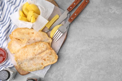 Photo of Delicious fish and chips served on gray table, flat lay. Space for text