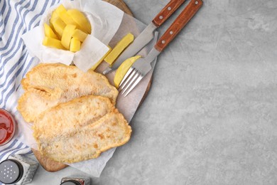 Delicious fish and chips served on gray table, flat lay. Space for text