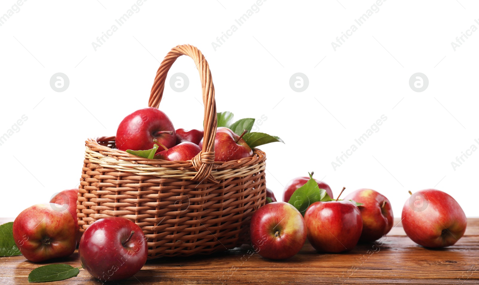 Photo of Ripe red apples and leaves on wooden table against white background