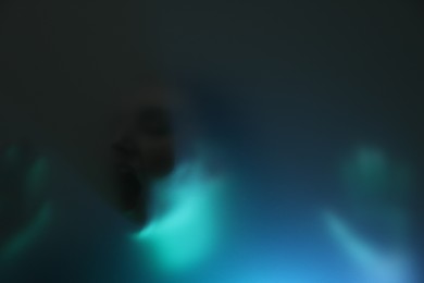 Photo of Silhouette of creepy ghost behind glass against color background