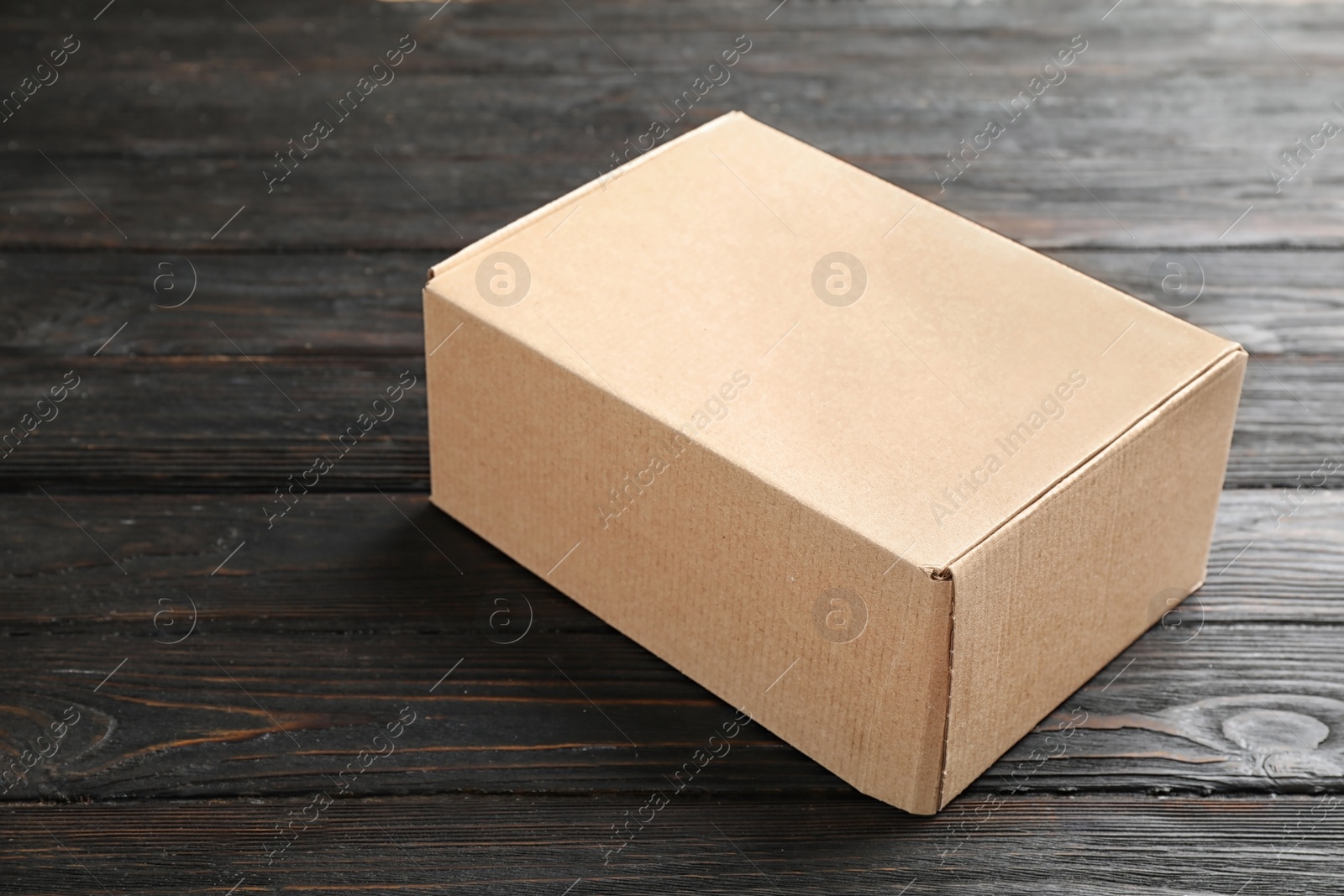 Photo of Closed cardboard box on dark wooden table