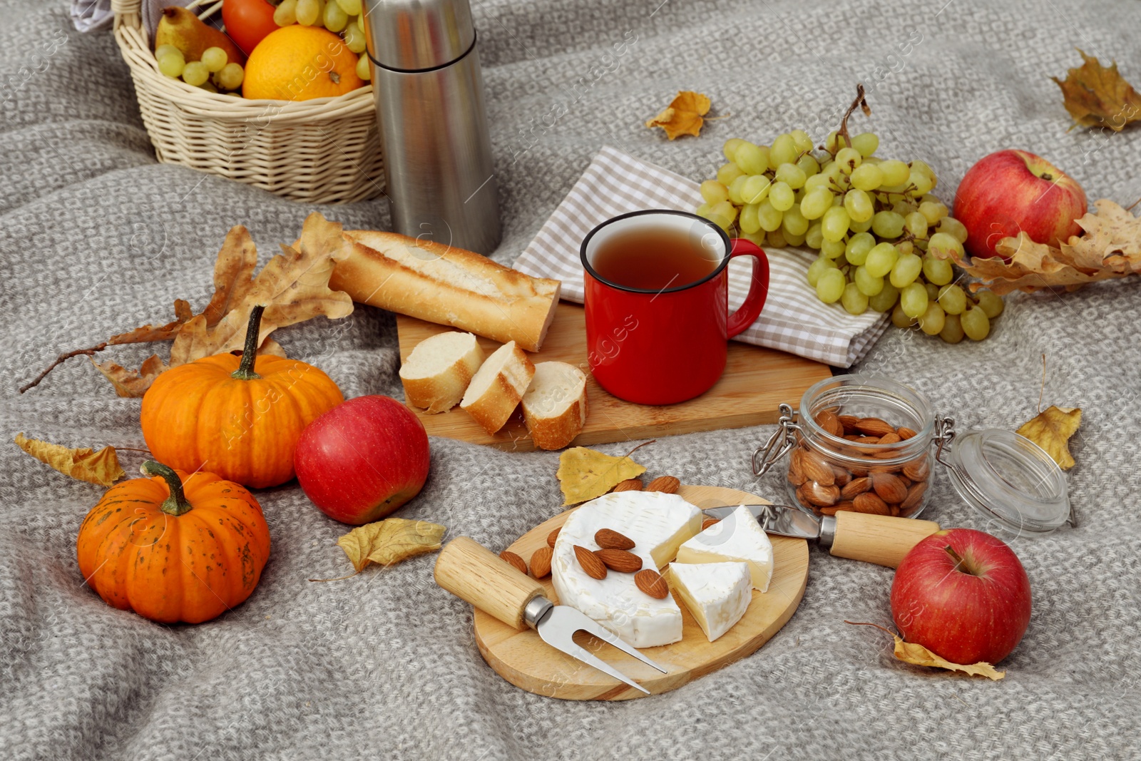 Photo of Blanket with picnic basket, snacks and autumn leaves