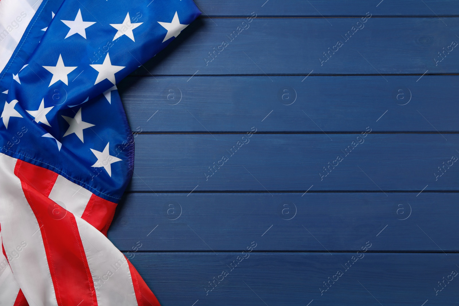 Photo of American flag on blue wooden table, top view with space for text. Memorial Day