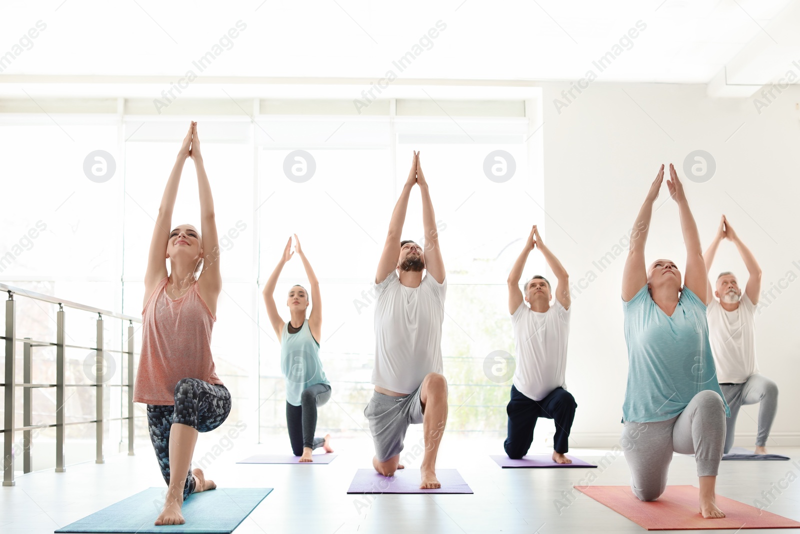 Photo of Group of people in sportswear practicing yoga indoors