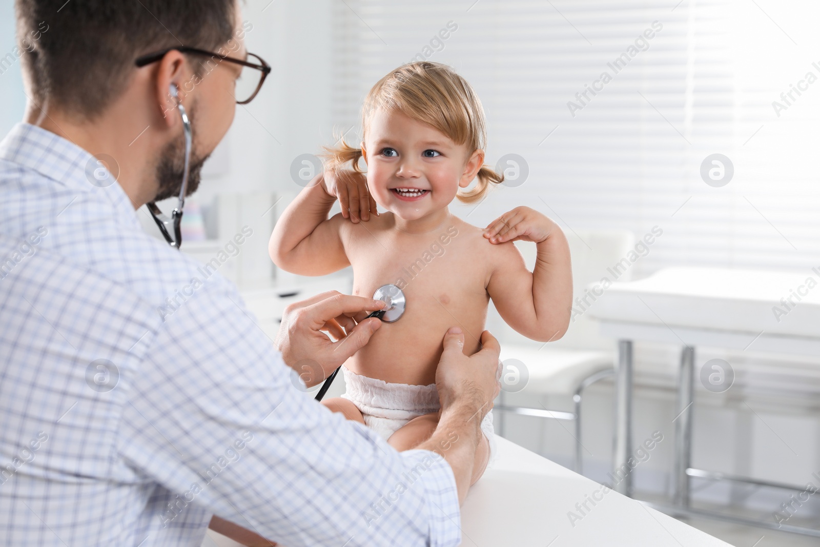 Photo of Pediatrician examining baby with stethoscope in clinic