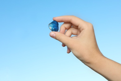 Photo of Woman holding shattuckite gemstone against blue background, closeup