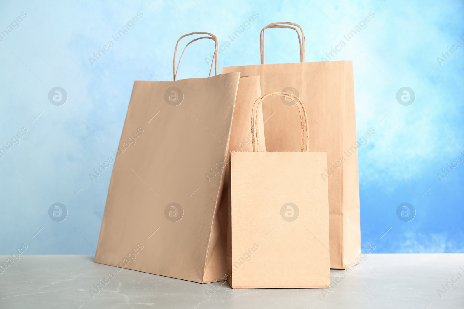 Photo of Mockup of paper shopping bags on table against color background