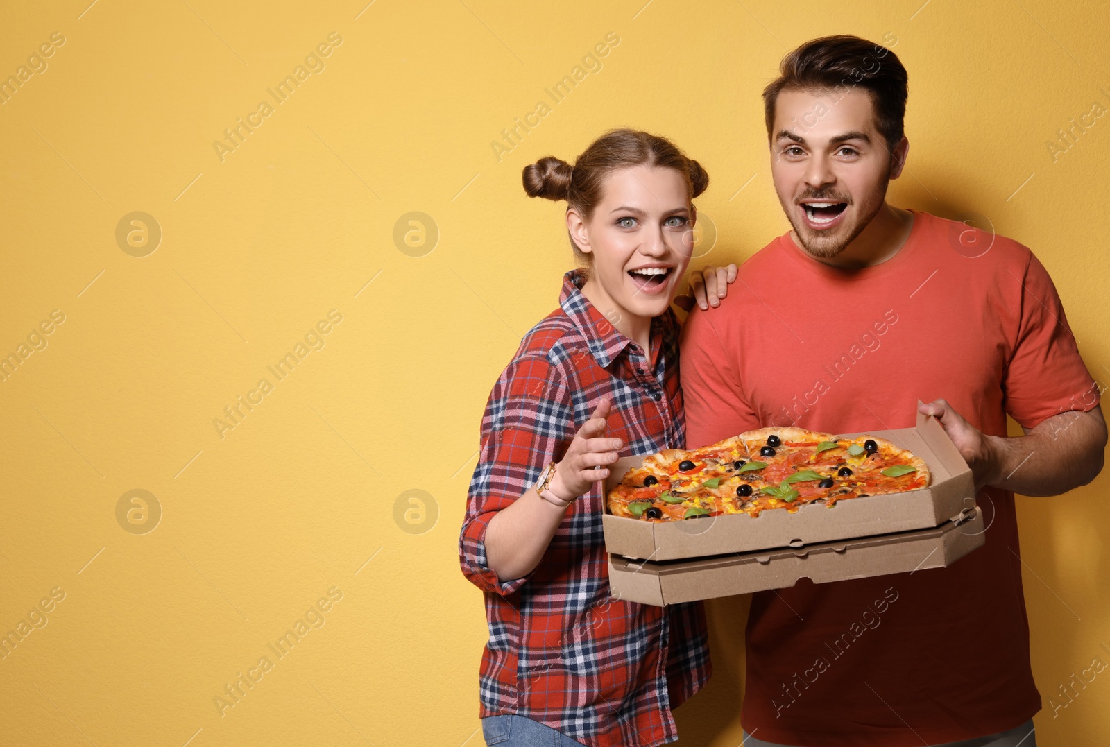 Photo of Attractive young couple with delicious pizza on color background