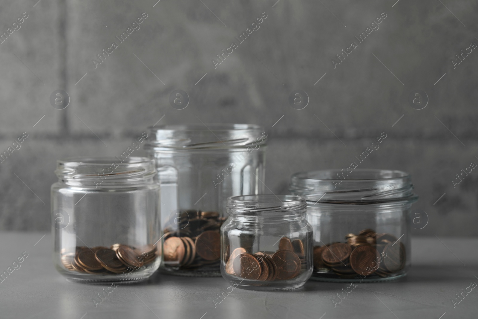 Photo of Glass jars with coins on grey table