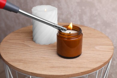 Lighting candle with gas lighter on wooden coffee table indoors