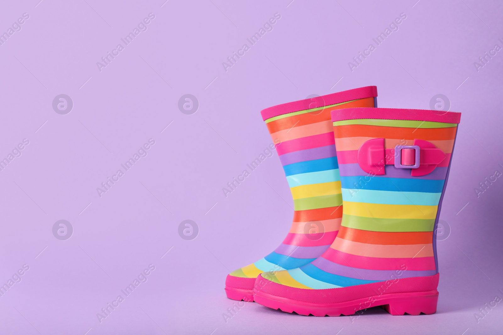 Photo of Pair of striped rubber boots on violet background, Space for text