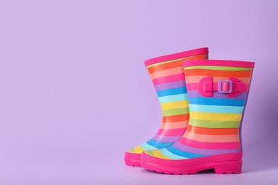 Photo of Pair of striped rubber boots on violet background, Space for text