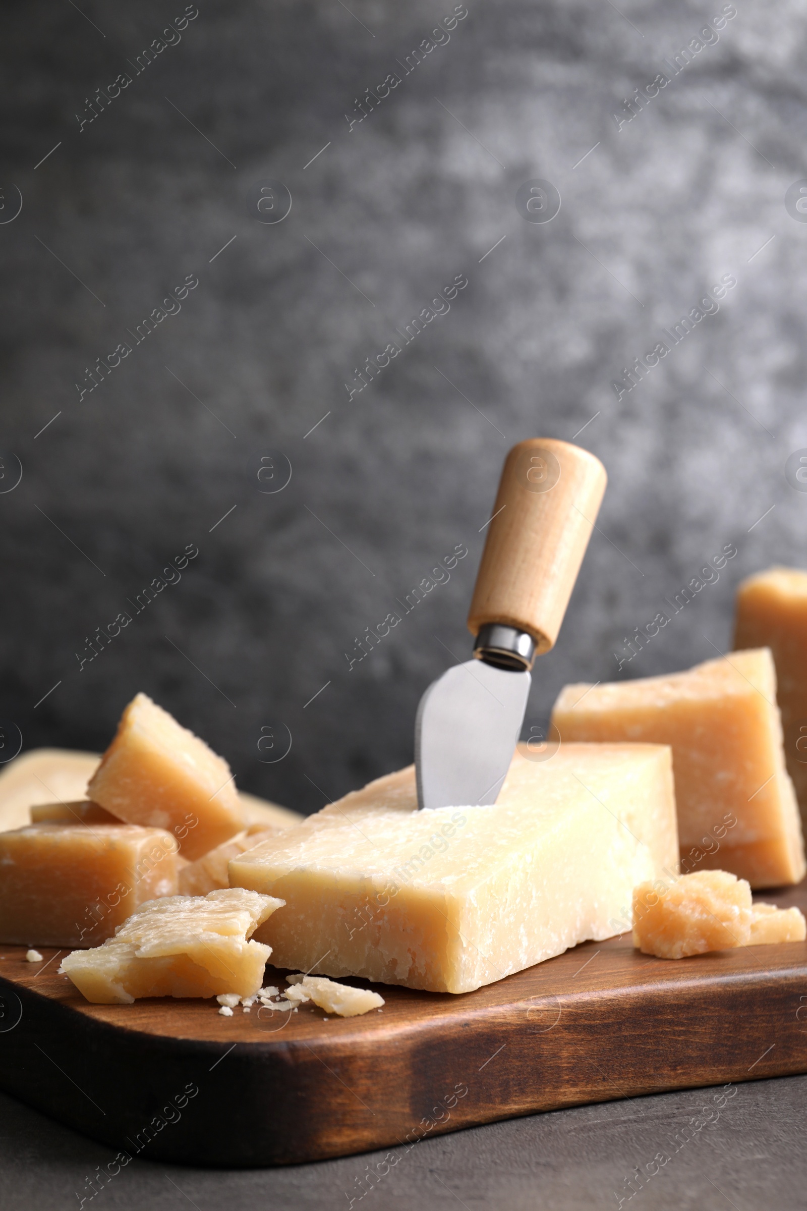 Photo of Parmesan cheese with knife on grey table