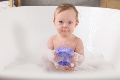 Photo of Cute little baby with sponge bathing in tub at home