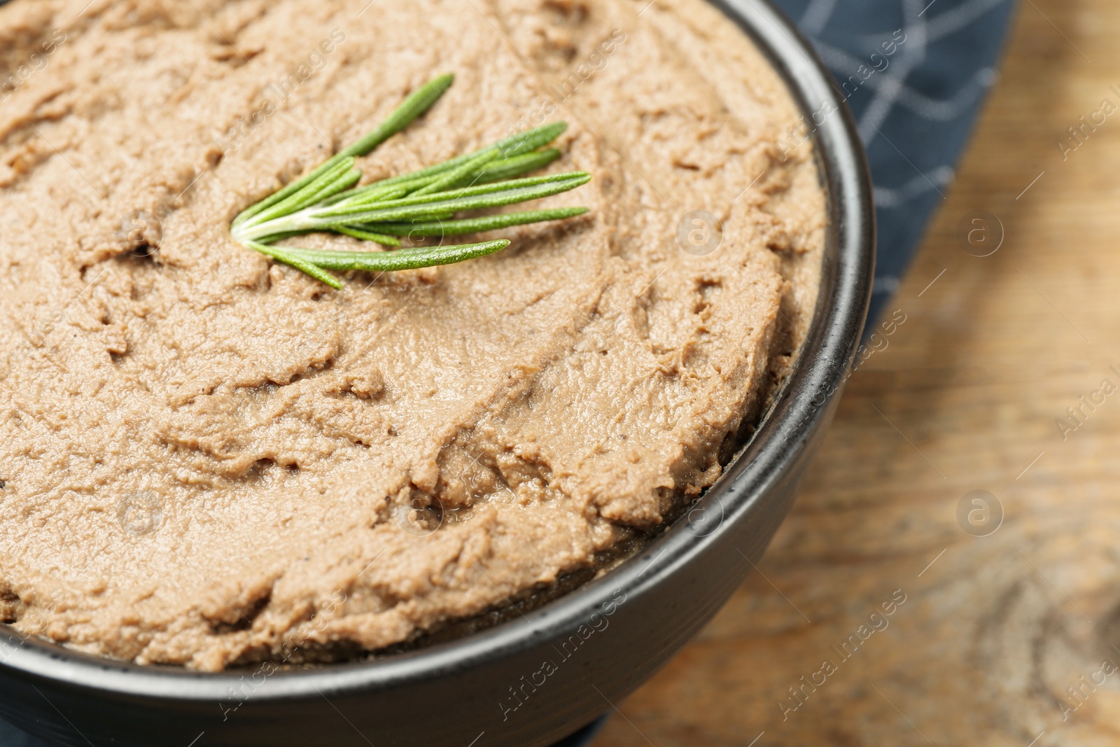 Photo of Tasty liver pate with rosemary in bowl on table, closeup