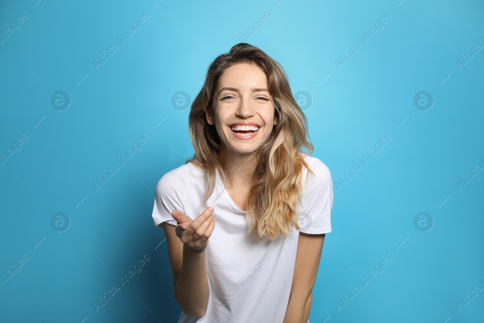 Photo of Cheerful young woman laughing on light blue background