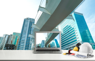 Image of Laptop with engineer equipment on table and modern cityscape