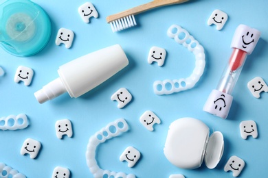 Flat lay composition with small plastic teeth and dental care items on color background