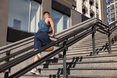 Photo of Man running up stairs outdoors on sunny day, low angle view