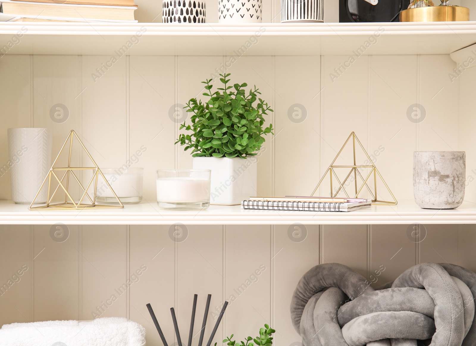 Photo of White shelving unit with plant and different decorative stuff