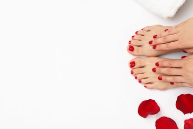 Photo of Woman with stylish red toenails after pedicure procedure and rose petals on white background, top view. Space for text
