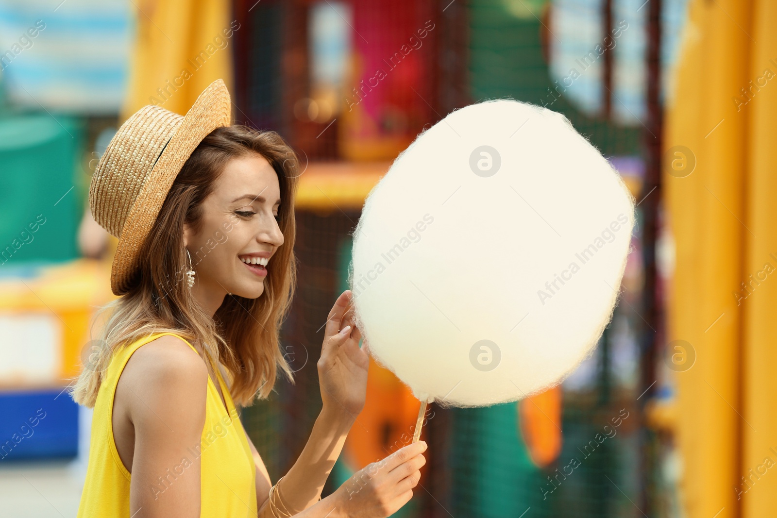 Photo of Happy young woman with cotton candy in amusement park