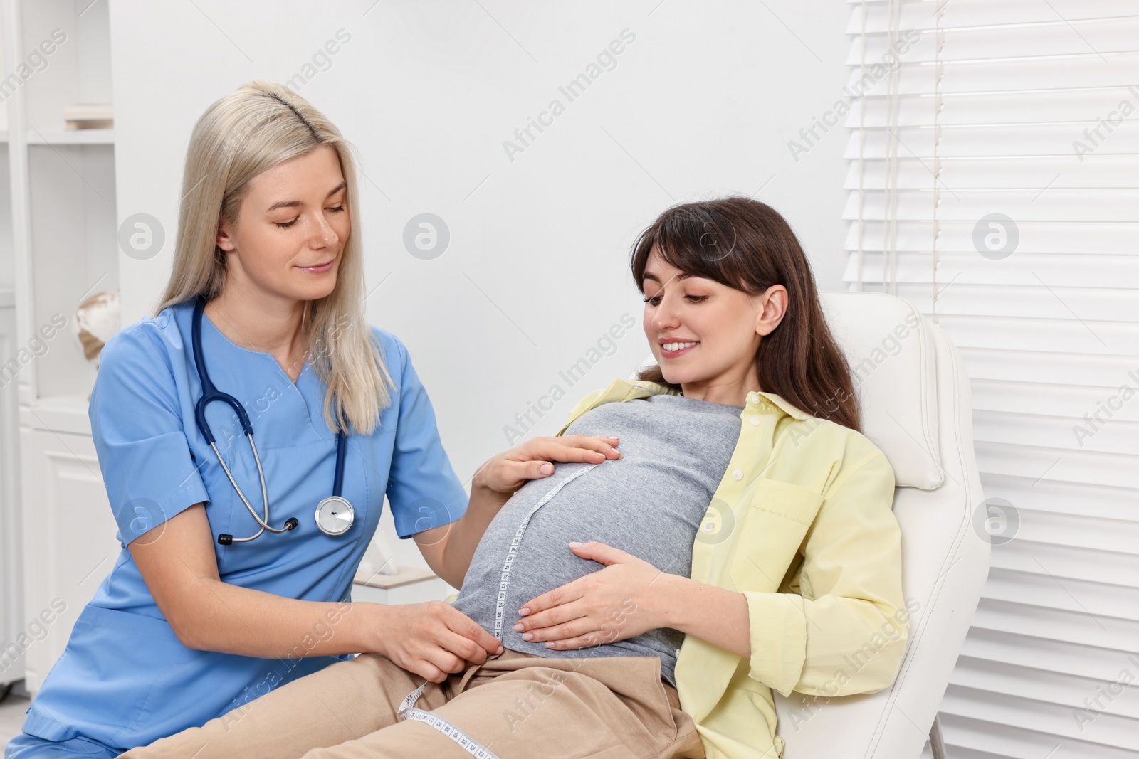 Photo of Pregnancy checkup. Doctor measuring patient's tummy in clinic