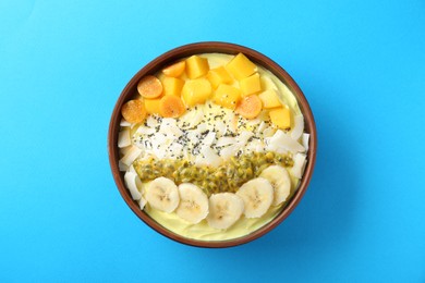 Photo of Tasty smoothie bowl with fresh fruits on light blue background, top view