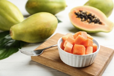 Fresh diced papaya in bowl on white wooden table