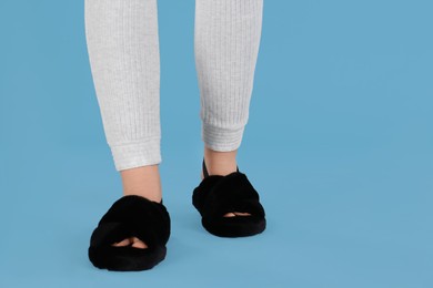 Photo of Woman in fluffy slippers on light blue background, closeup