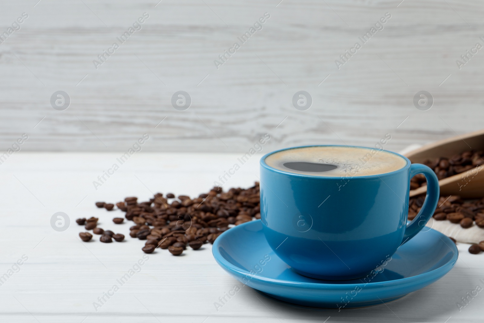 Photo of Cup of aromatic hot coffee and beans on white table, space for text