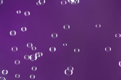 Photo of Beautiful transparent soap bubbles on purple background