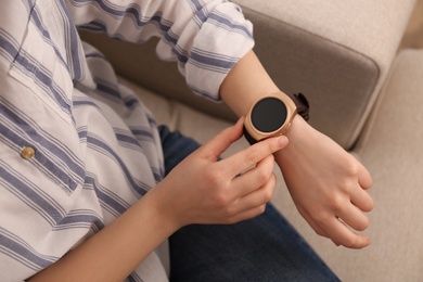 Photo of Young woman using smart watch at home, closeup view