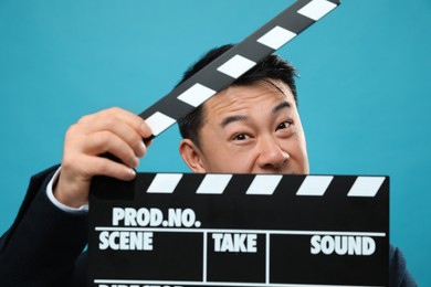 Photo of Asian actor clapperboard on light blue background. Film industry