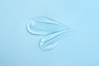 Photo of Swatches of cosmetic gel on light blue background, top view