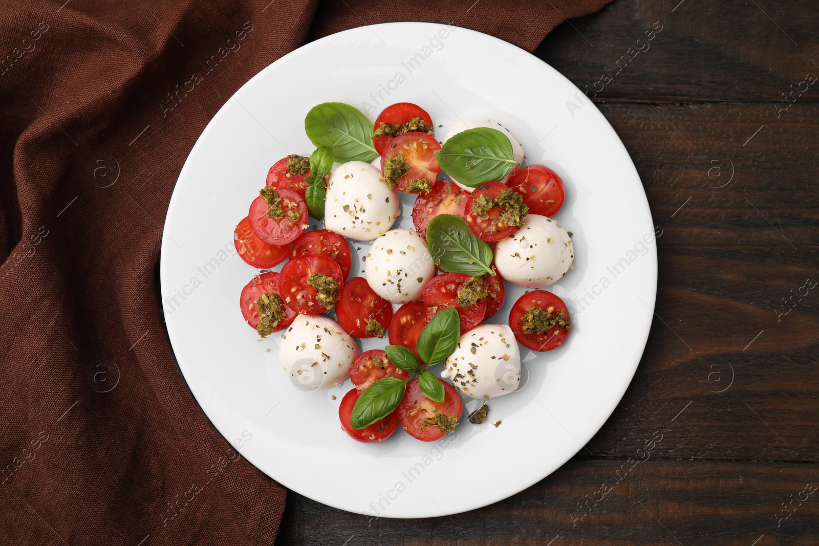 Photo of Tasty salad Caprese with tomatoes, mozzarella balls and basil on wooden table, top view