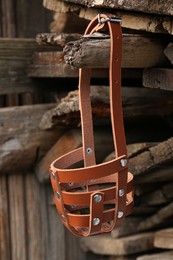 New brown dog muzzle hanging near firewood