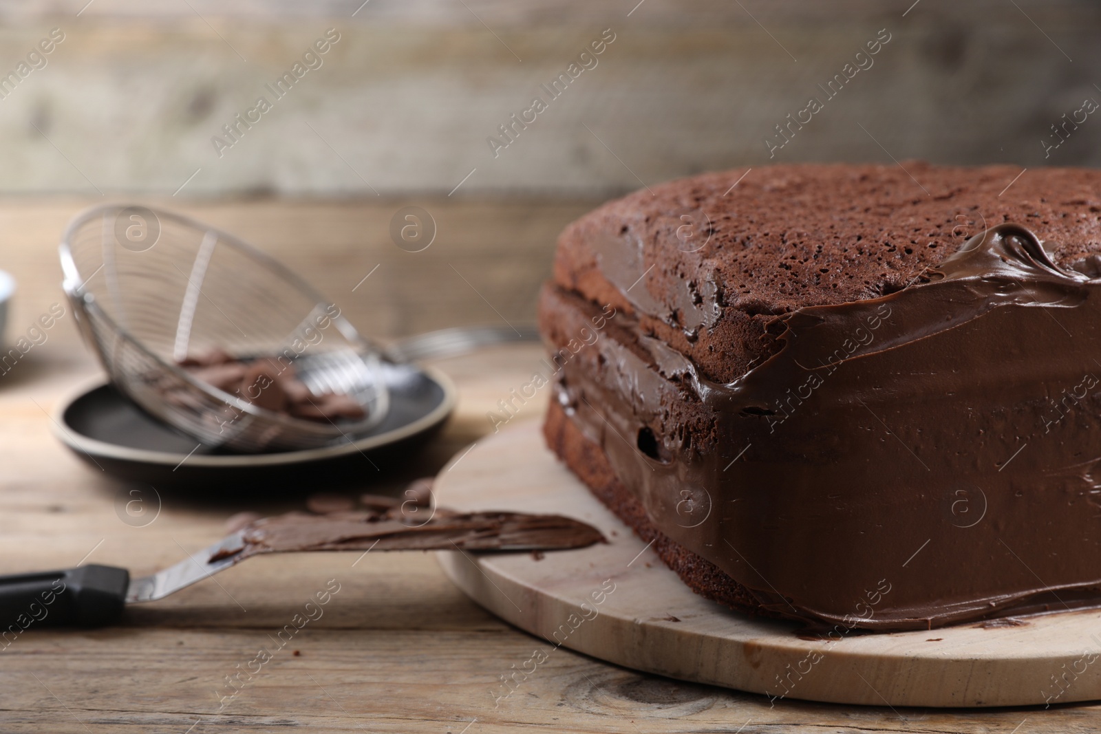 Photo of Delicious homemade layer cake with chocolate cream on wooden table, closeup