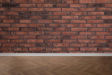 Wooden floor and empty brick wall indoors