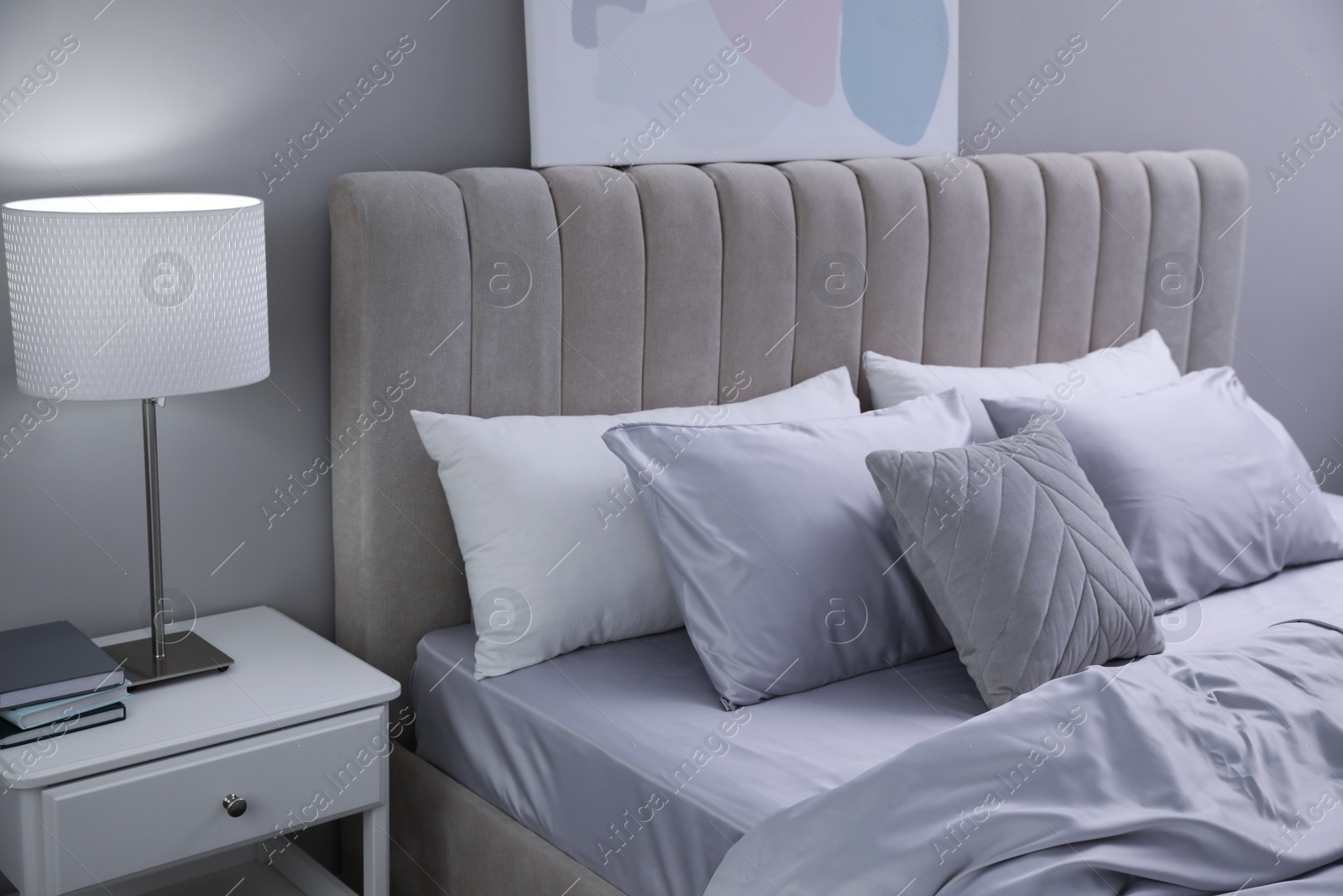 Photo of Cozy bed with soft silky bedclothes in light room