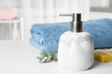 Marble dispenser, eucalyptus and soap bar on white table