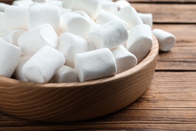 Photo of Delicious puffy marshmallows on wooden table, closeup