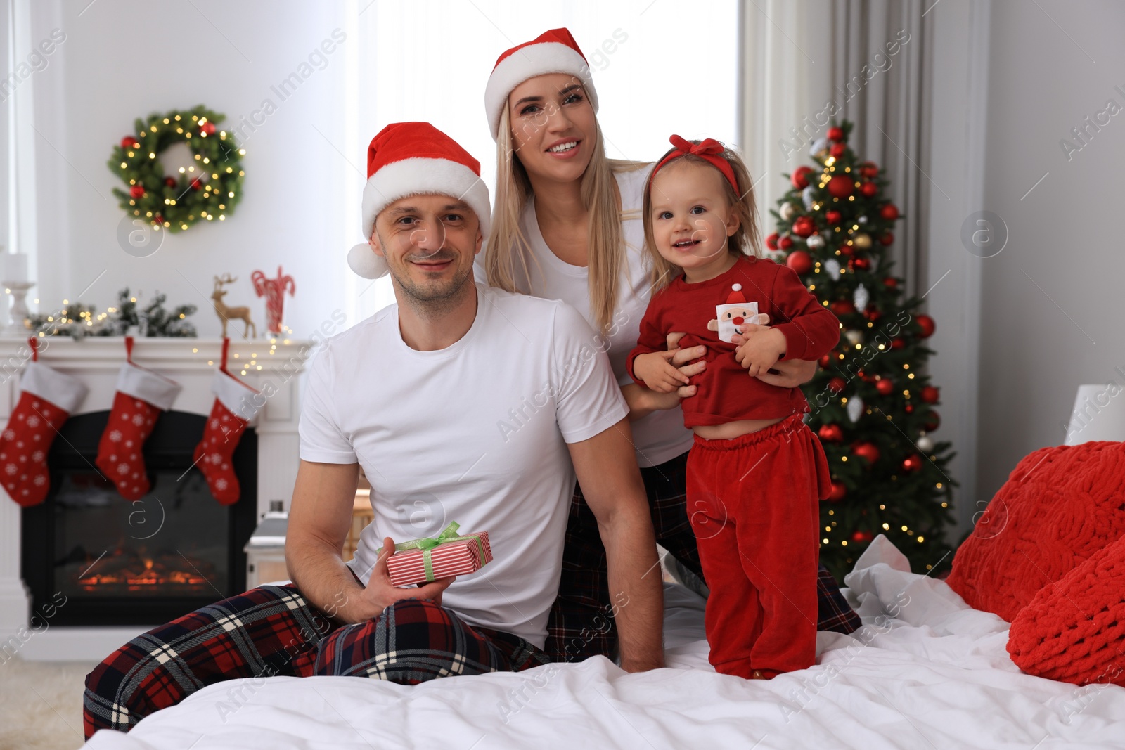 Photo of Happy family with Santa hats in room decorated for Christmas