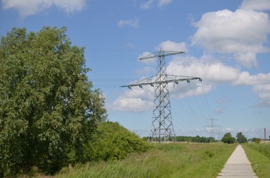 Photo of Modern high voltage towers in field on sunny day