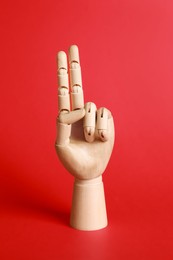 Wooden hand model on red background. Mannequin part