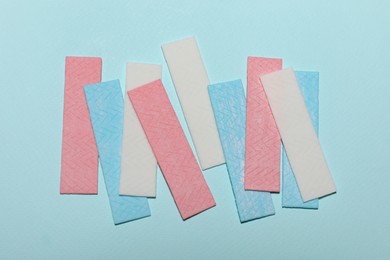 Sticks of tasty chewing gum on light blue background, flat lay