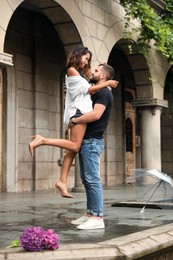 Photo of Young couple enjoying time together under rain on city street