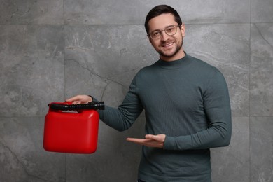 Photo of Handsome man showing red canister near grey wall
