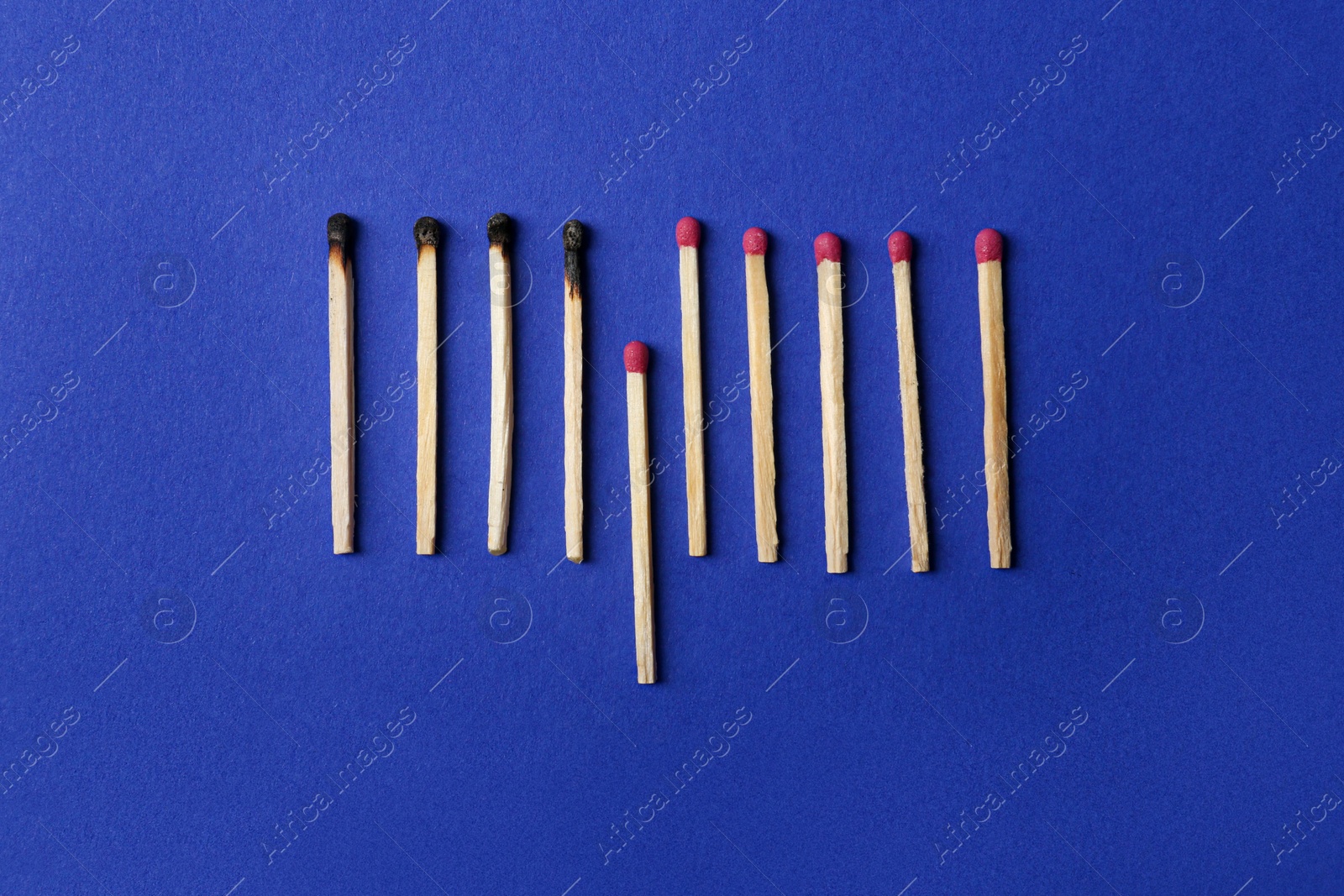 Photo of Burnt and whole matches on blue background, flat lay. Stop destruction concept